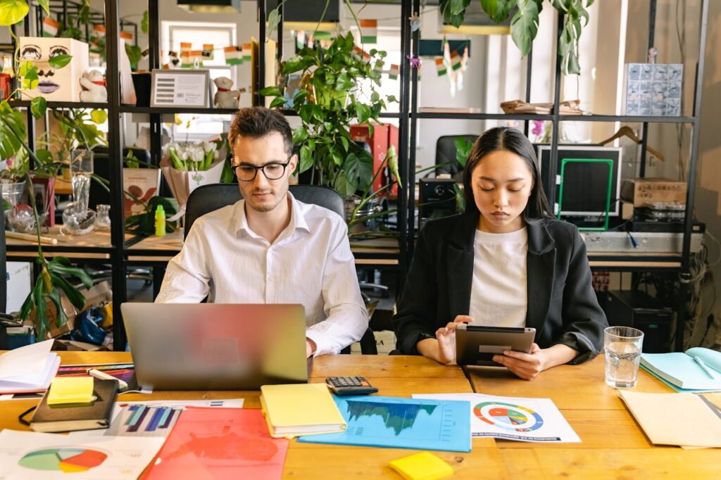 Crafting Captivating Headlines: Your awesome post title goes here Two professionals working with laptops and tablets in a modern coworking space surrounded by plants.